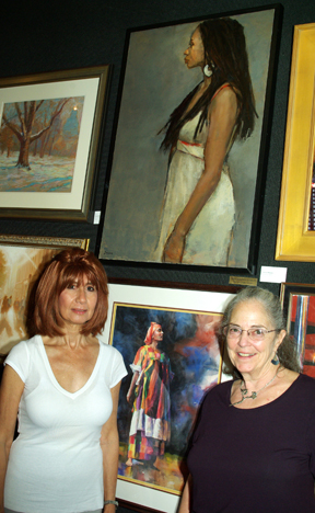 Carole Dakake, left, winner of the ART TIMES award for her painting “Woman in White”.  Cornelia Seckel is to the right of the painting. 