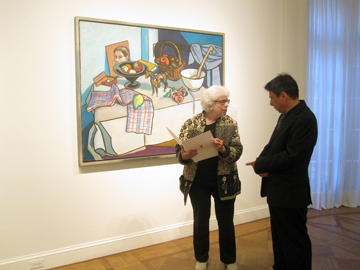 Curator Bruce Weber (L) speaking with a member of the press at the National Academy, NYC. Leland Bell works on wall